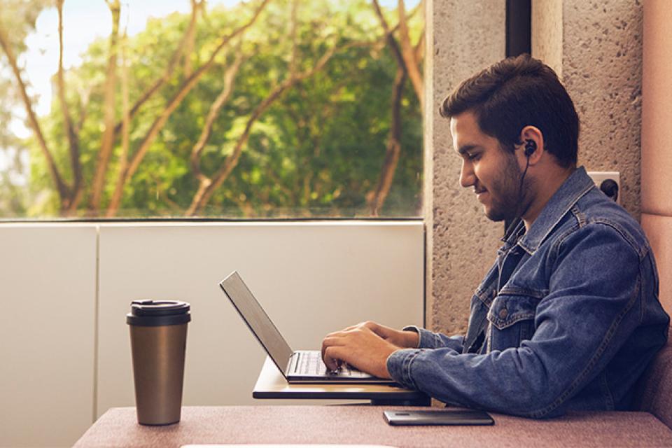 A student sits at a desk studying with headphones in.