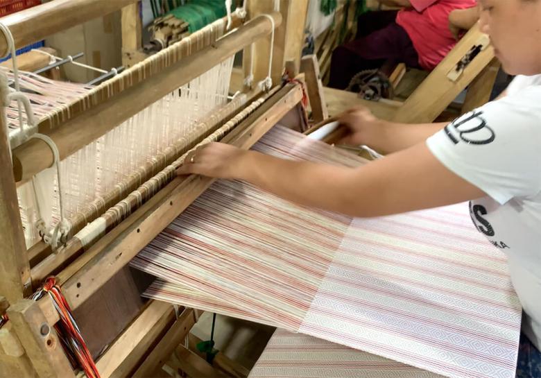 man weaving fabric with loom