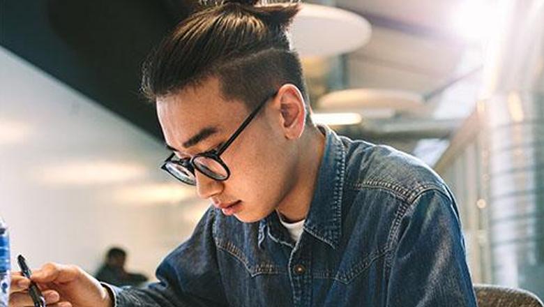 A male student sits at a table studying