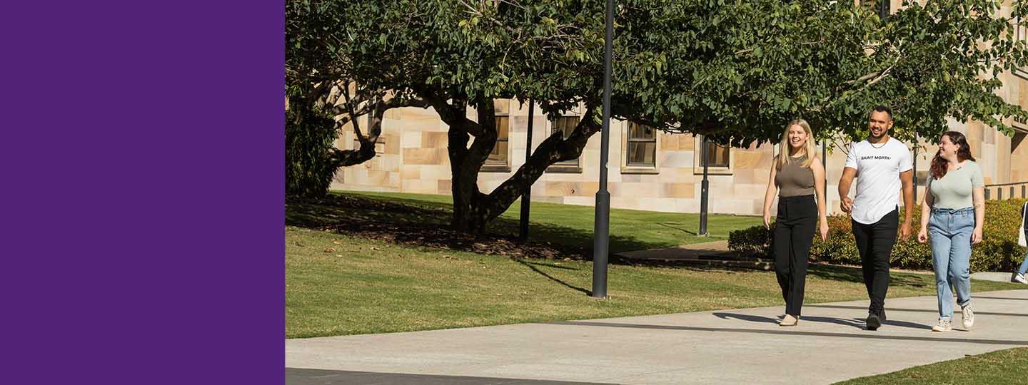 Students walking on a path at UQ's St Lucia campus with sandstone buildings in background