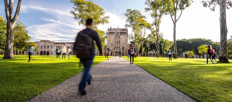 Student walking on path through Great Court towards Forgan Smith