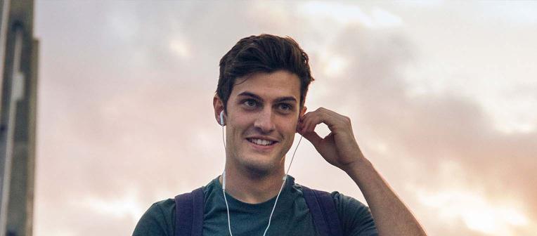 Man walking with headphones in his ears, in the sky. 