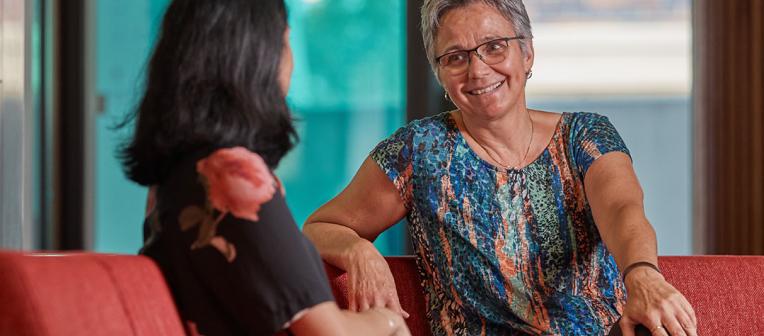 Counsellor speaking with a women on a red couch.