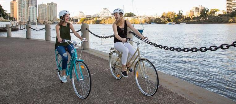 2 girls riding bikes along the river