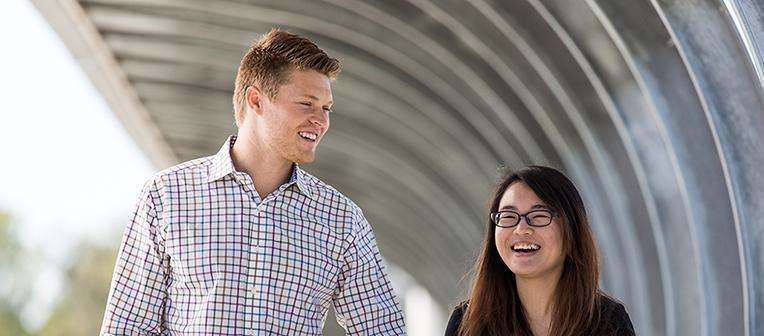 2 people walking across a bridge