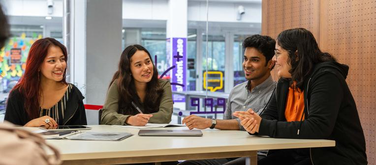 International students talking at a table in the BEL Student Base.