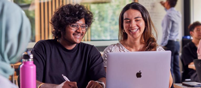 UQ students look at a laptop in a classroom