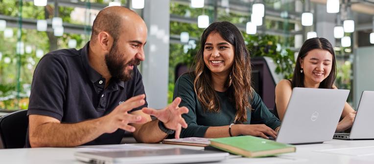 UQ students studying in light-filled classroom at desks with laptops