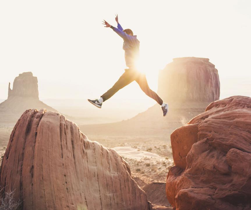 A man jumping between two rocks in the desert.