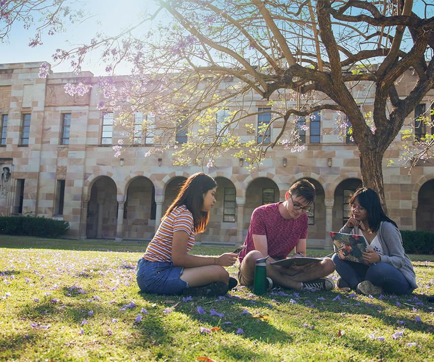 Three students sitting on the UQ Great Court. 