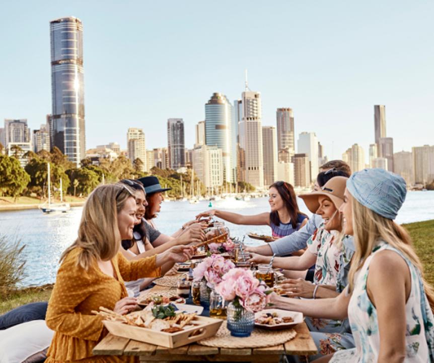 Friends having a picnic in a park with Brisbane's Central Business District at the back