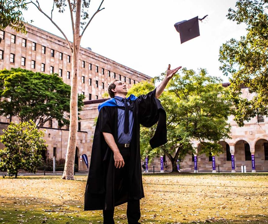 Male student throwing mortarboard in the sky. 