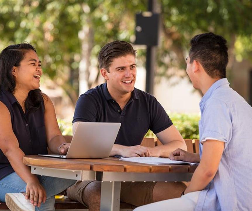 Three students sitting at outdoor table
