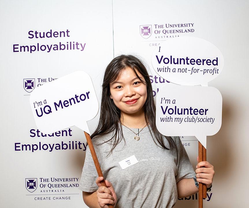 Student holding up lollipop signs of what she did (volunteered and mentored) to become more employable