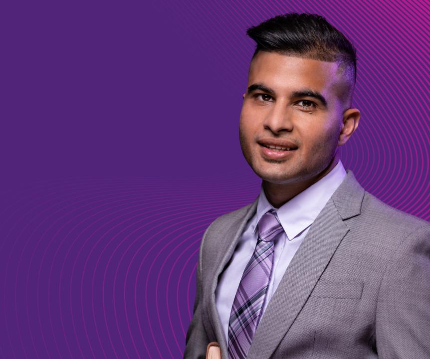 A postgraduate student wearing a suit and tie, smiling.