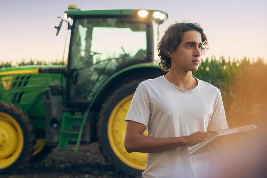 A student on Gatton campus standing in front of a tractor.