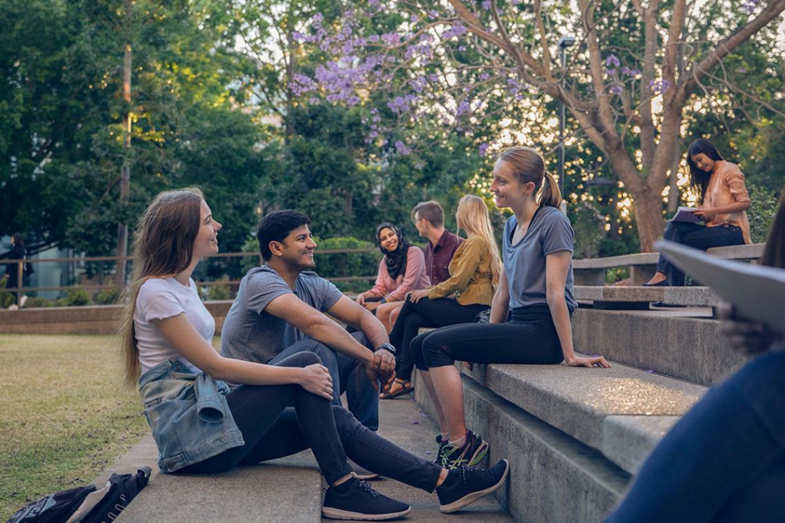 A group of students sitting together near the Biological Sciences Library at St Lucia campus.