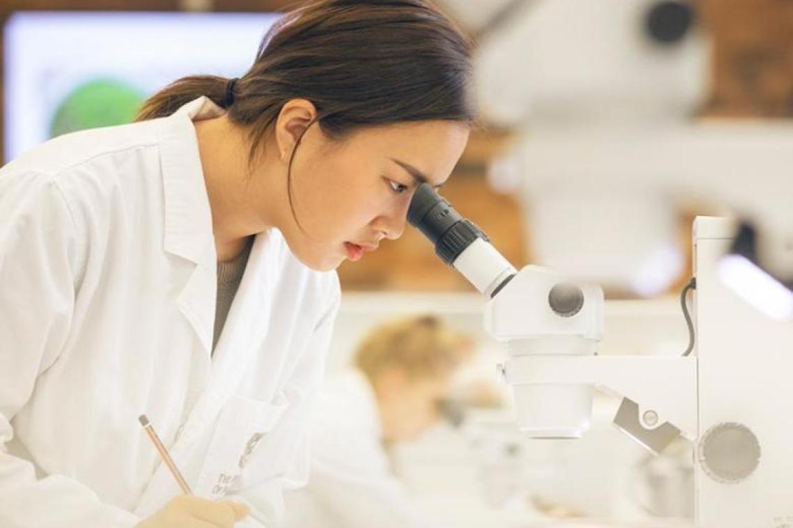 Student looking in microscope. 