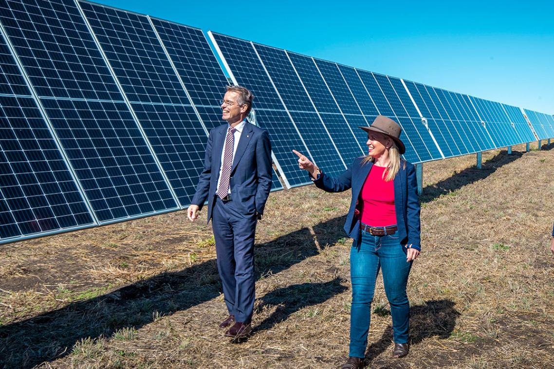Man and woman walk past solar panels. 