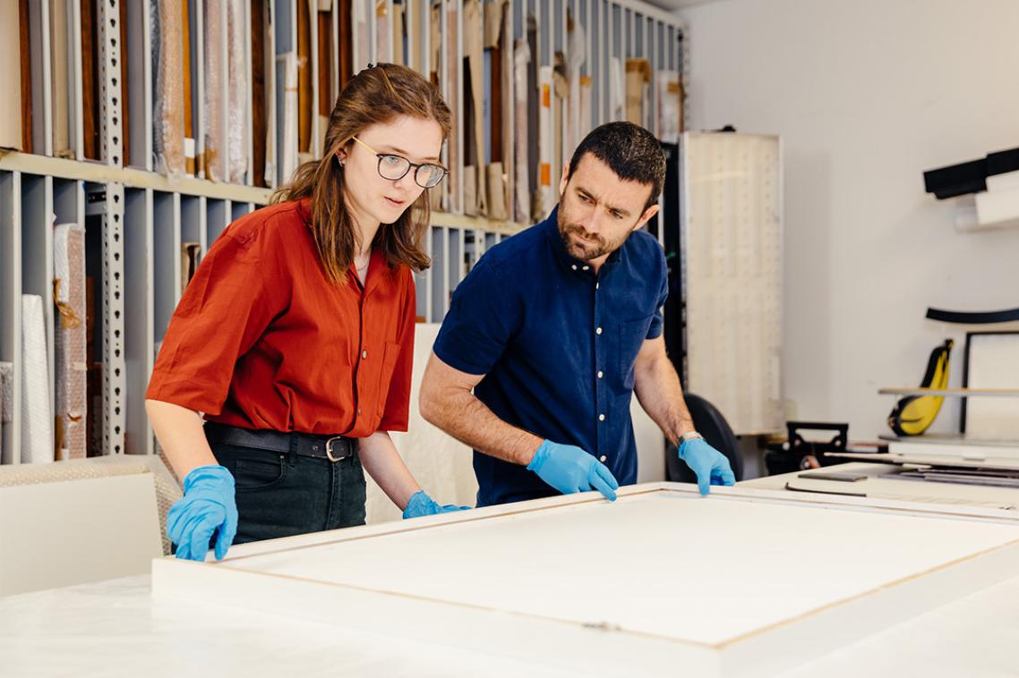 Two students handling an artwork behind the scenes in the UQ Art Museum