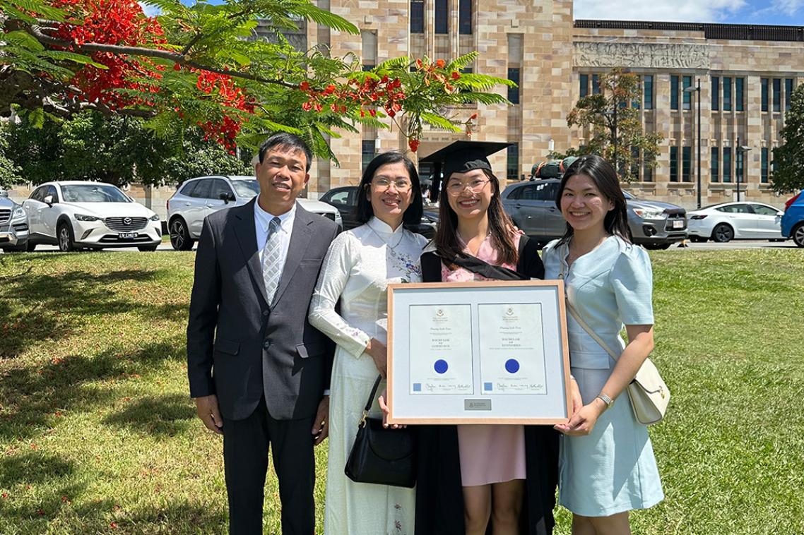 A graduate standing with her family in from of Forgan Smith