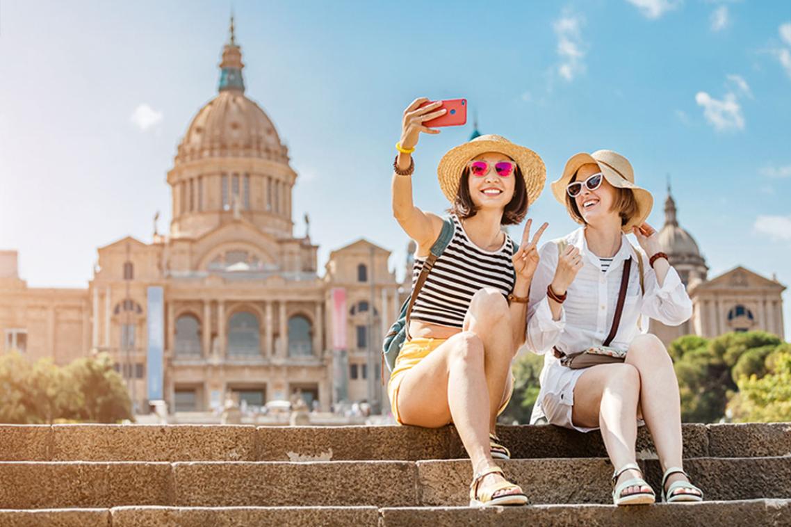 Two people sitting on sunny church steps while taking a selfie