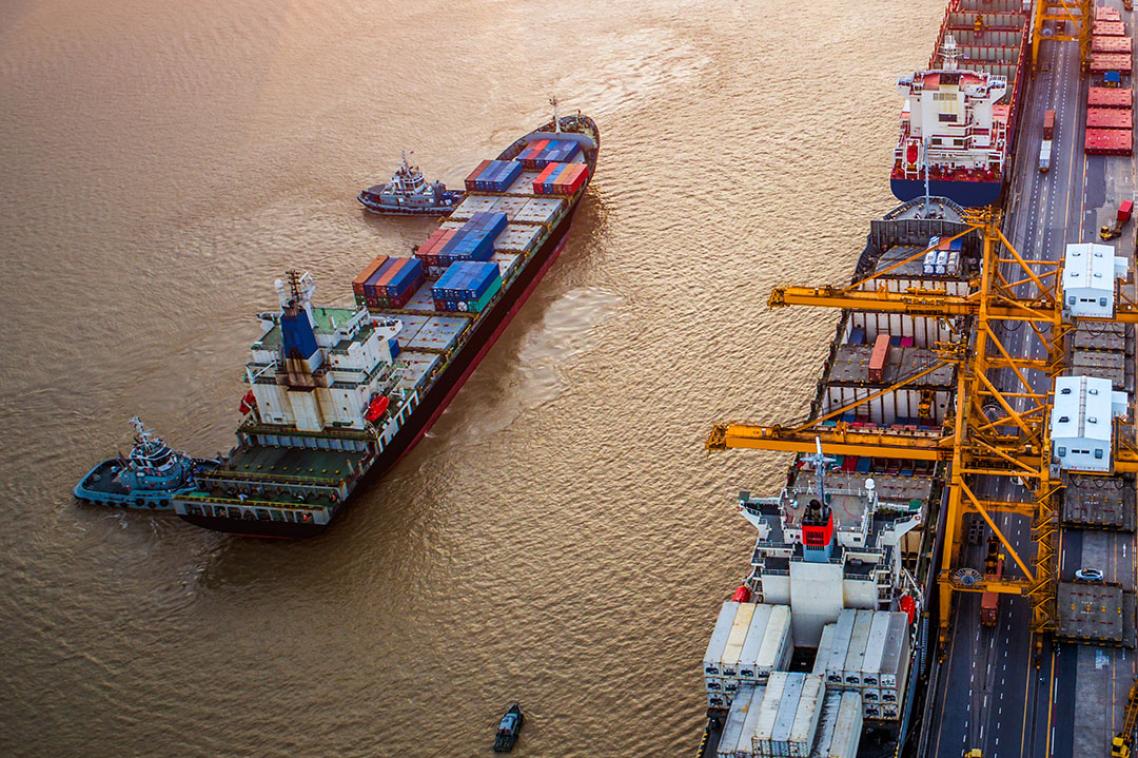 A cargo ship, seen from above, approaches a dock