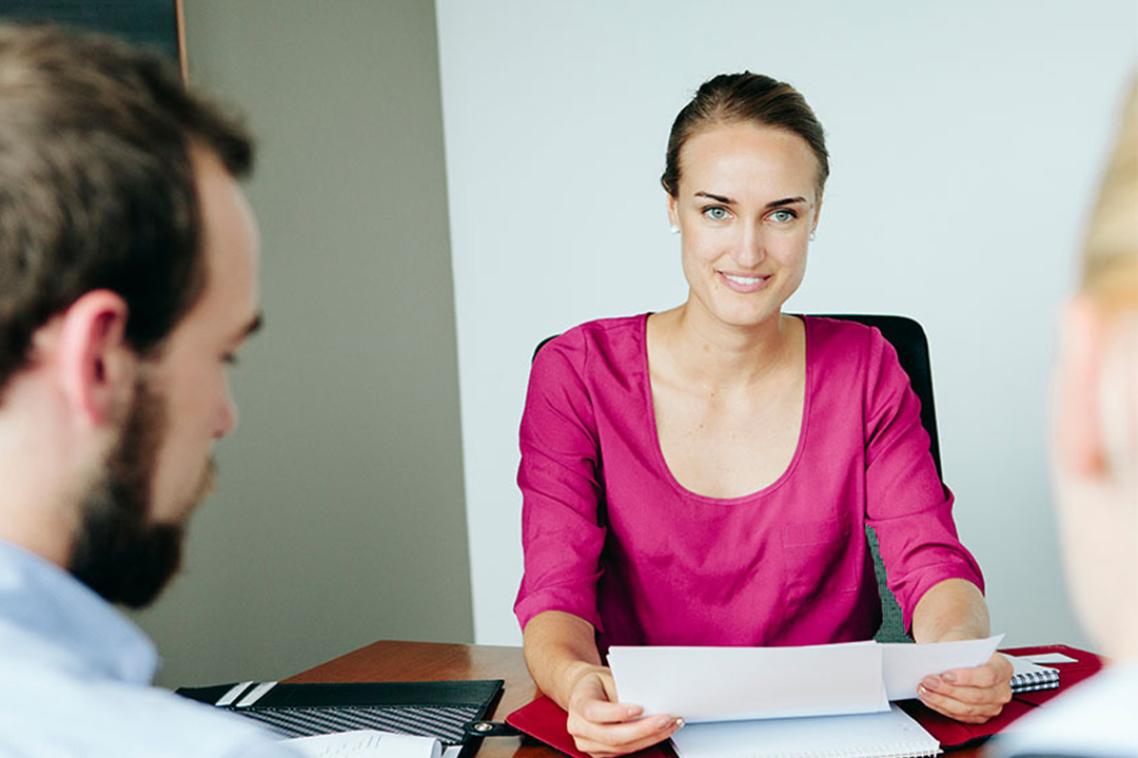 A woman in a business setting discusses a document with two other people