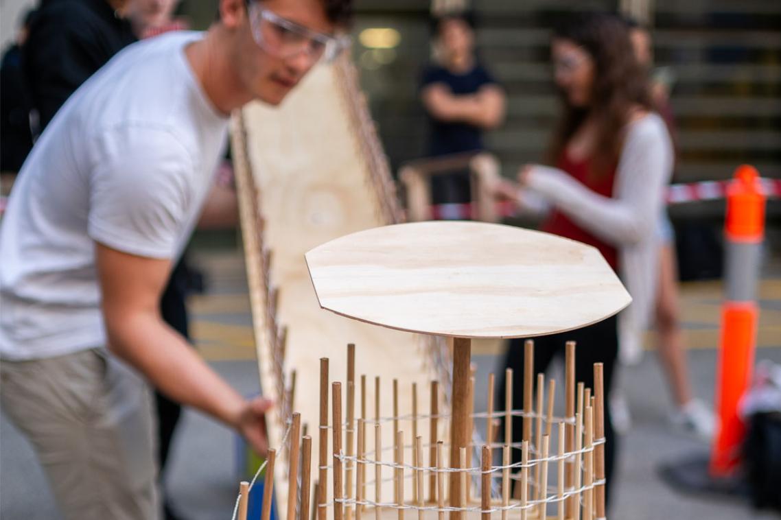 An engineering student designs and inspects a model of a bridge