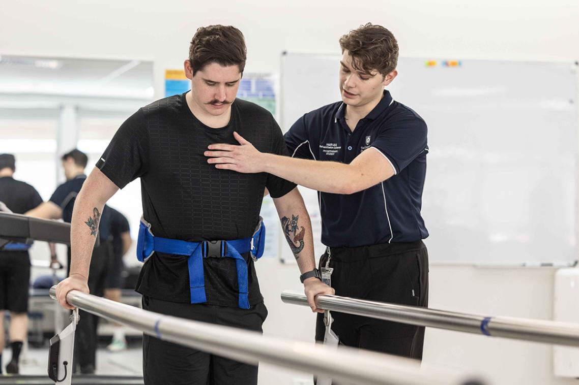 Physiotherapy student assist patient in rehab exercises
